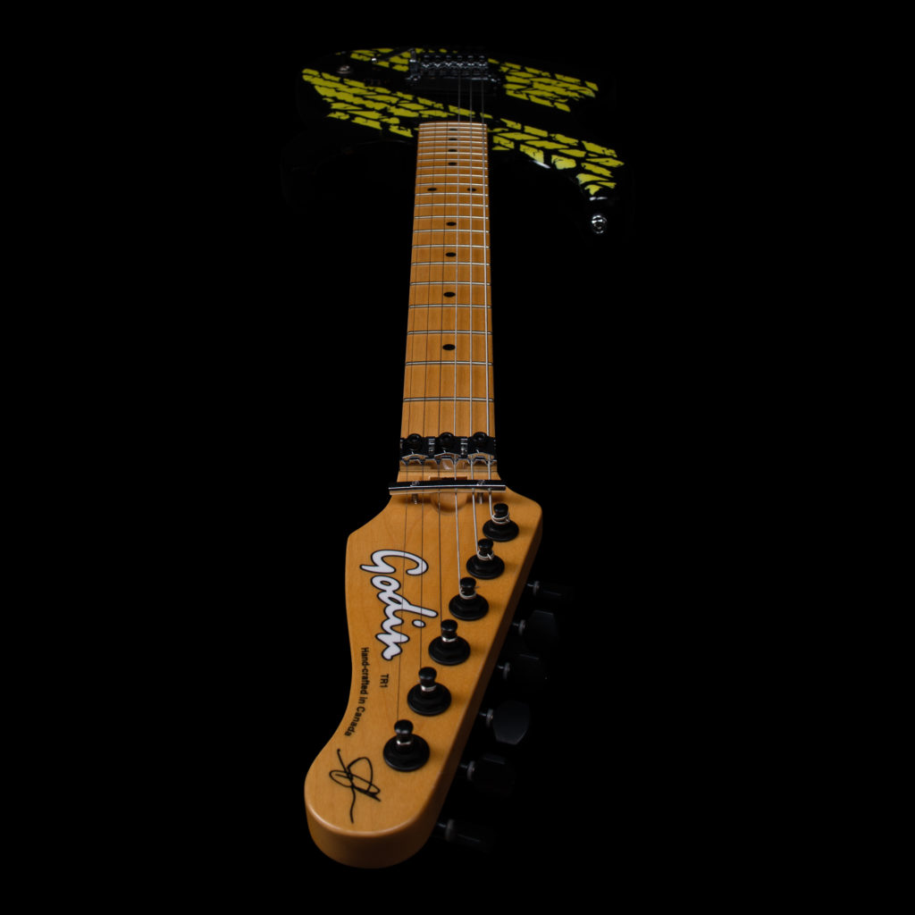 A black Godin guitar with a yellow tire tread mark graphics. A black Godin guitar with a yellow tire tread mark graphics.