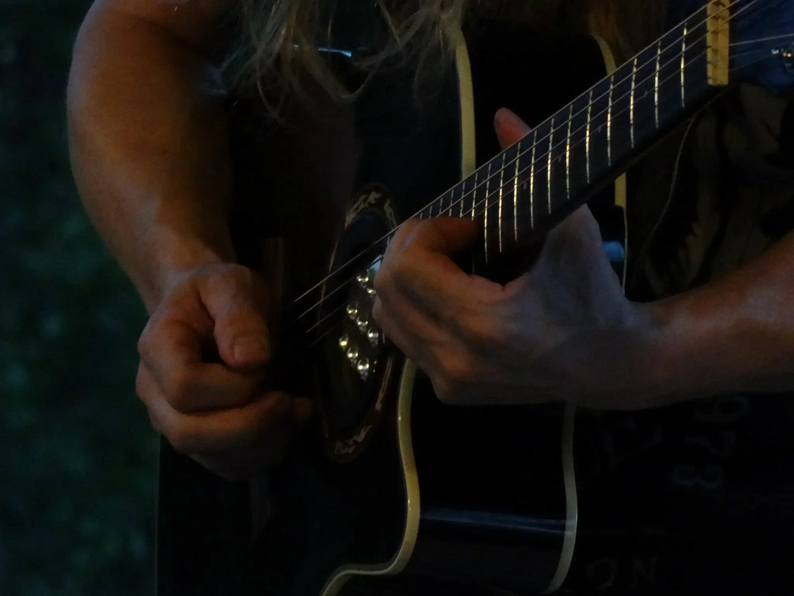 Close up angled shot of a black guitar being played Close up angled shot of a black guitar being played