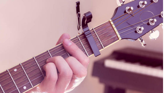 Guitar being played using a capo. Guitar being played using a capo.