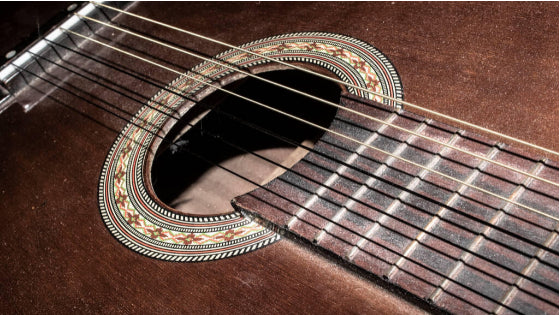 A close up view of a brown guitar sound hole area A close up view of a brown guitar sound hole area