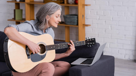 Woman taking online guitar lessons Woman taking online guitar lessons
