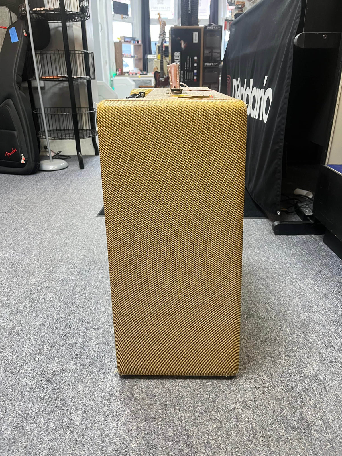 A 1957 Fender Bassman 5F6 Narrow Panel 40-Watt 4x10" Guitar Combo w/Flight Case by Fender, featuring vintage tweed style, stands in a music store, evoking the iconic sound and design of the classic '57 era.