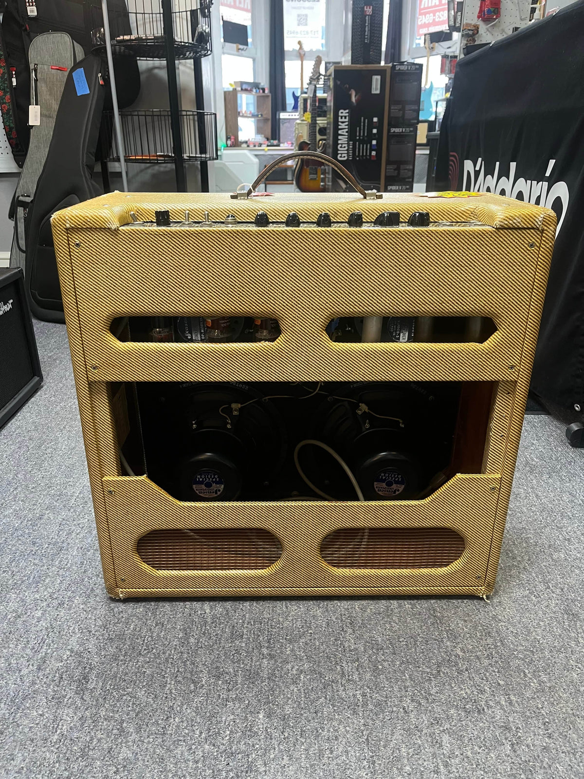 A Fender 1957 Bassman 5F6 Narrow Panel 40-Watt 4x10" Guitar Combo with tweed covering, open back, and top-mounted controls is displayed in a music store, complete with a flight case.
