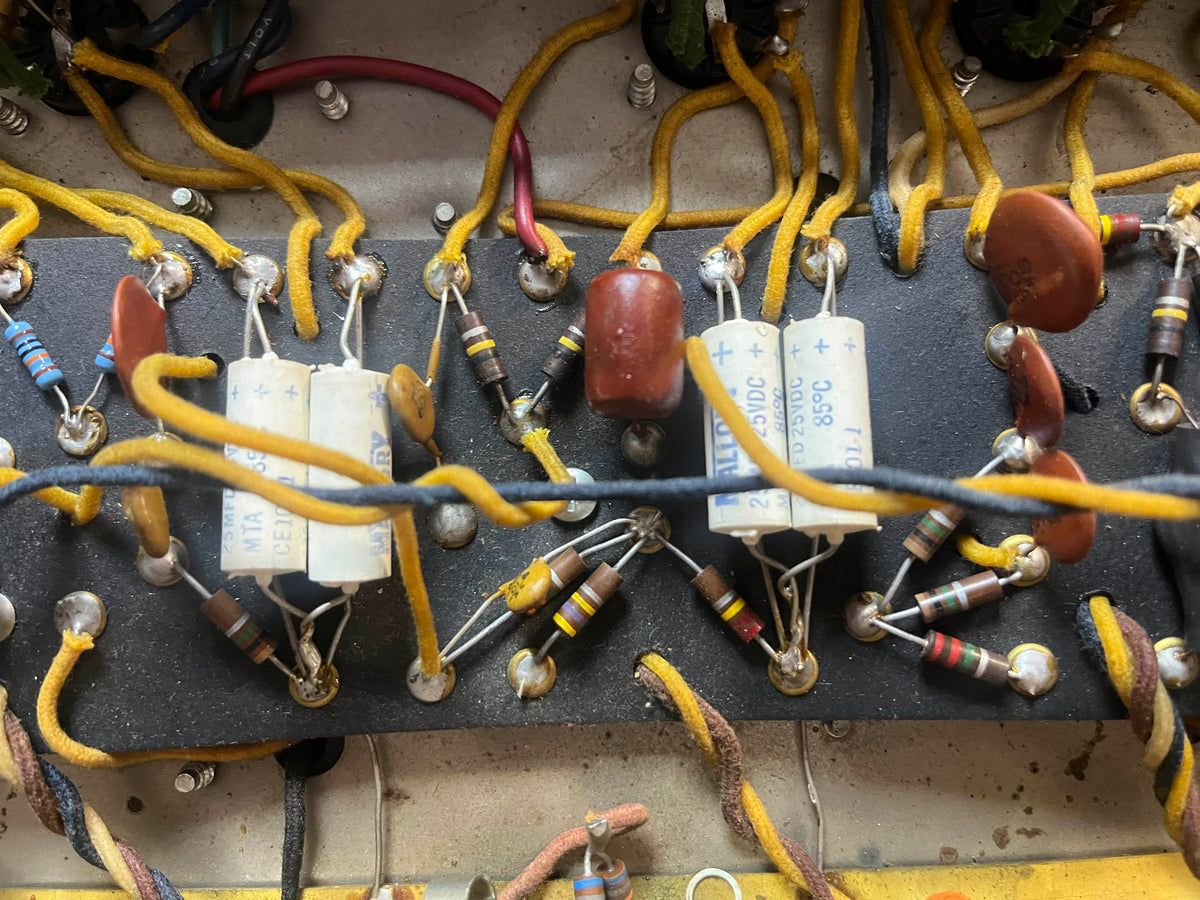 Close-up of vintage resistors, capacitors, and yellow wiring on a circuit board inside a 1965 Fender Deluxe Reverb AB763 Pre-CBS Blackface (Serial A 06439) amplifier.