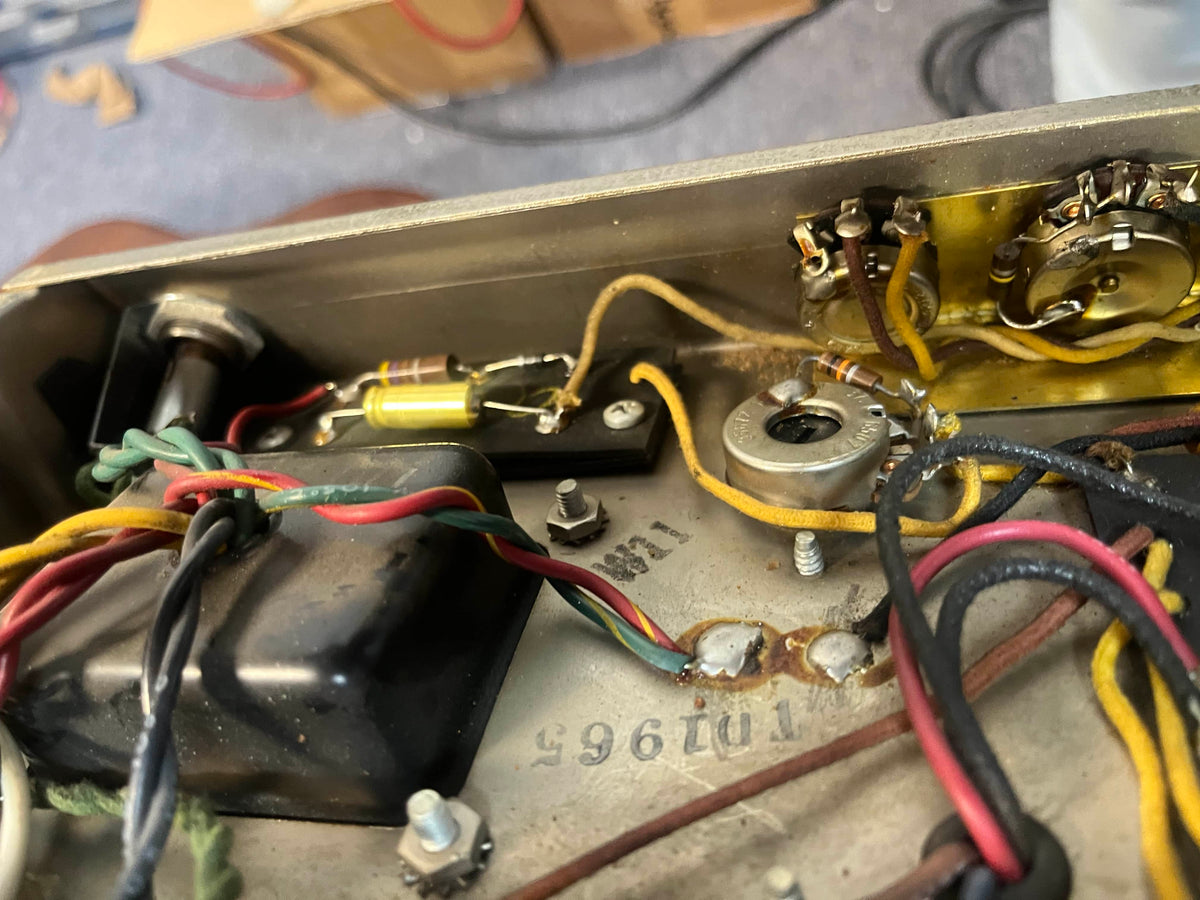 Close-up of electronic components and wiring inside a 1965 Fender Deluxe Reverb AB763 (Pre-CBS Blackface, Serial A 06439) showing resistors, a potentiometer, and colored wires connected to terminals in this vintage tube amp.
