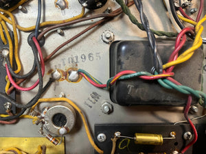 Close-up of electronic parts and colored wires inside a 1965 Fender Deluxe Reverb AB763 (Pre-CBS Blackface, Serial A 06439), with "10701965" and "1ZM" stamped on the metal.