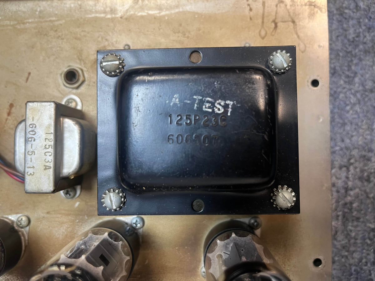 Close-up of a black metal transformer labeled "A-TEST 125P23C 606611" mounted on a beige chassis—typical of components in vintage tube amps like the Fender 1965 Deluxe Reverb AB763 Pre-CBS Blackface Serial A 06439.