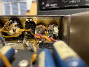 Close-up of electronic components and wiring inside a metal chassis, featuring potentiometers and capacitors from a 1965 Fender Super Reverb - Black Panel, available for local pickup at Guitars on Main.