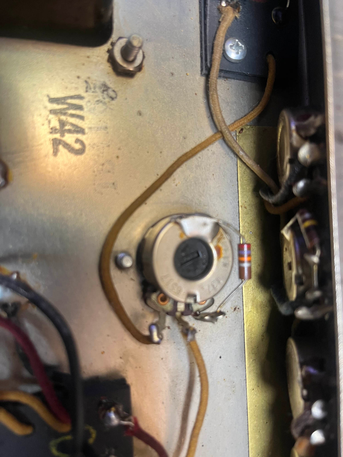 Close-up of electronic components inside a metal enclosure, with wires to a rotary potentiometer and resistor—showcasing the craftsmanship of the 1965 Fender Super Reverb - Black Panel, available for local pickup at Guitars on Main.