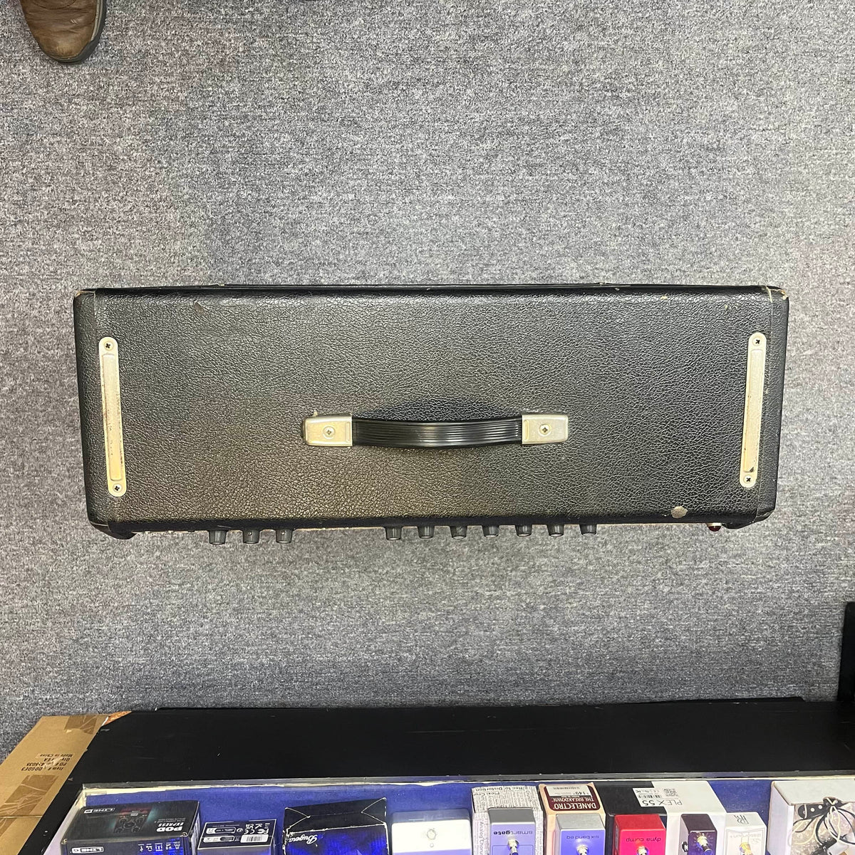 A 1965 Fender Super Reverb Black Panel amp head from Guitars on Main rests on a gray carpet, evoking vintage tones, with several guitar pedals visible below. Available for local pickup.