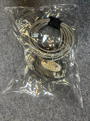 A coiled cable with a metallic connector, ideal for the 1966 Fender Black Panel Twin Reverb 2-Channel 85-Watt 2x12" Guitar Combo Amp w/Case by Fender, is sealed inside a clear plastic bag on a gray carpeted surface.
