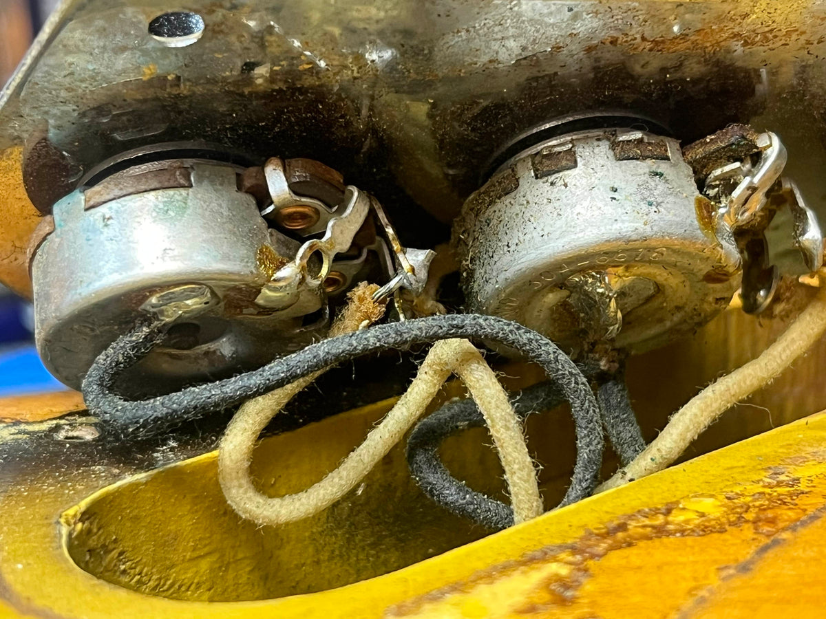 Close-up of two corroded potentiometers with frayed wires and original pickups in the cavity of a 1966 Fender Jazz Bass Natural Refinish w/Case by Fender.