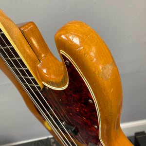 Close-up of a 1966 Fender Jazz Bass Natural Refinish by Fender, featuring visible scratches, dents, part of the neck, tortoiseshell pickguard, and original pickups; includes case.