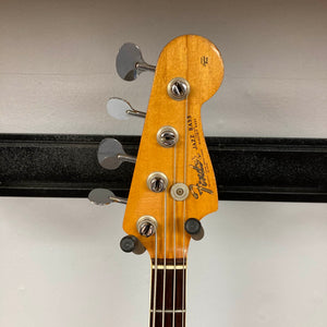 The headstock of a 1966 Fender Jazz Bass Natural Refinish w/Case by Fender features four tuning pegs, strings, and the iconic Fender logo, set against a simple light background.