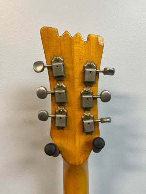 Back of a Mosrite 1967 Mosrite Mark I Vintage Guitar headstock showing six metal tuning pegs against a plain light wall—an icon of American guitar heritage.