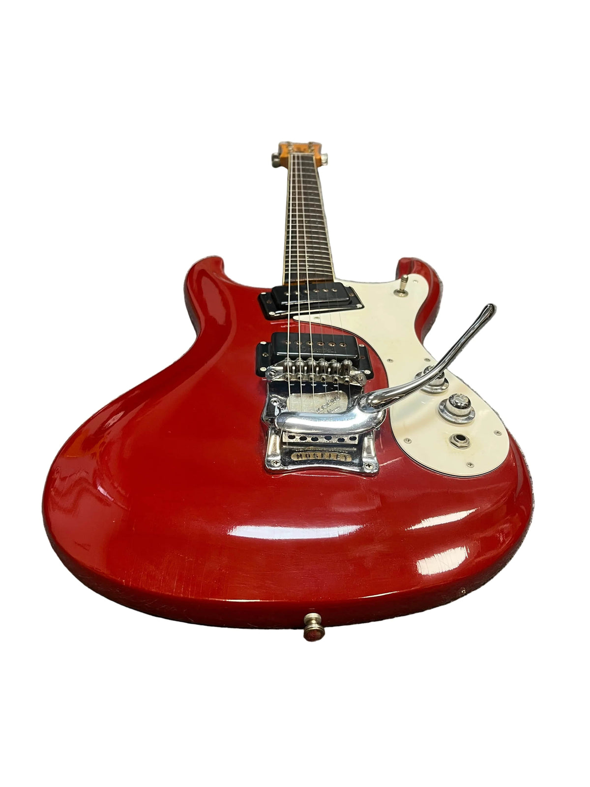 The 1967 Mosrite Mark I Vintage Guitar by Mosrite features a red body, white pickguard, black pickups, whammy bar, and control knobs—an iconic piece of American guitar history—photographed on a white background.