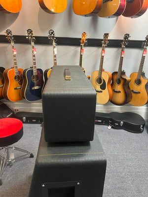 Several acoustic guitars hang on a wall in a music store, with a Marshall 1971 Lead Head JMP 1987 50 Watt amp (includes flight case) stacked in the foreground, delivering classic British tones. A red stool sits to the left.