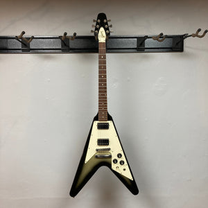 1979 Gibson Flying V Silverburst guitar on wall hook with original case, showcasing a unique vintage design and minor blemishes.