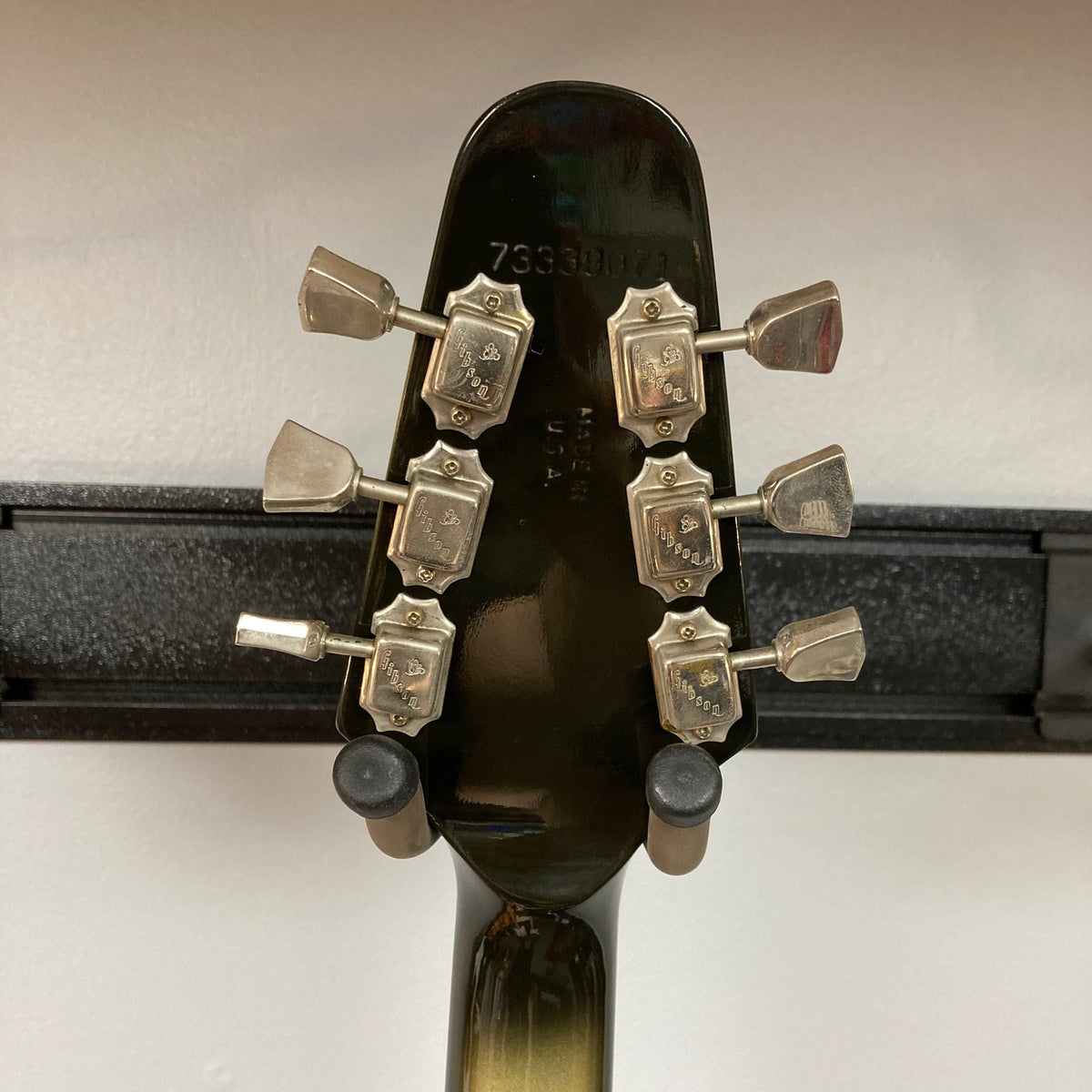 Close-up of a 1979 Gibson Flying V Silverburst guitar, showcasing its unique shape and minor blemishes, with an included original case.
