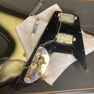 1979 Gibson Flying V Silverburst electric guitar with case, visible wires, and minor blemishes, highlighting its vintage charm and craftsmanship.