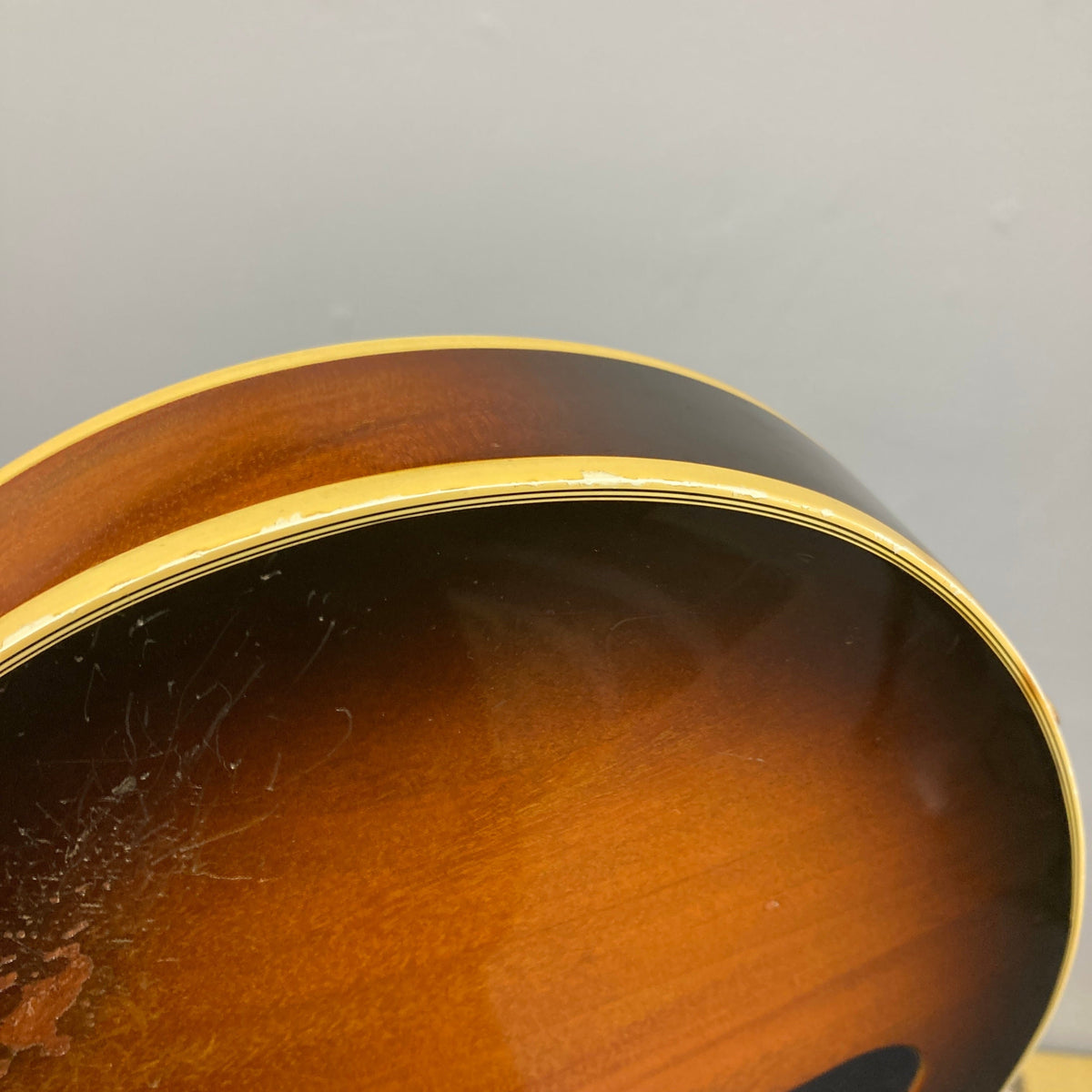 Close-up of the edge of a 1980 Gibson Les Paul Custom – Tobacco Sunburst w/OHSC, highlighting scratches and binding chips—classic signs of vintage wear on this iconic Gibson guitar.