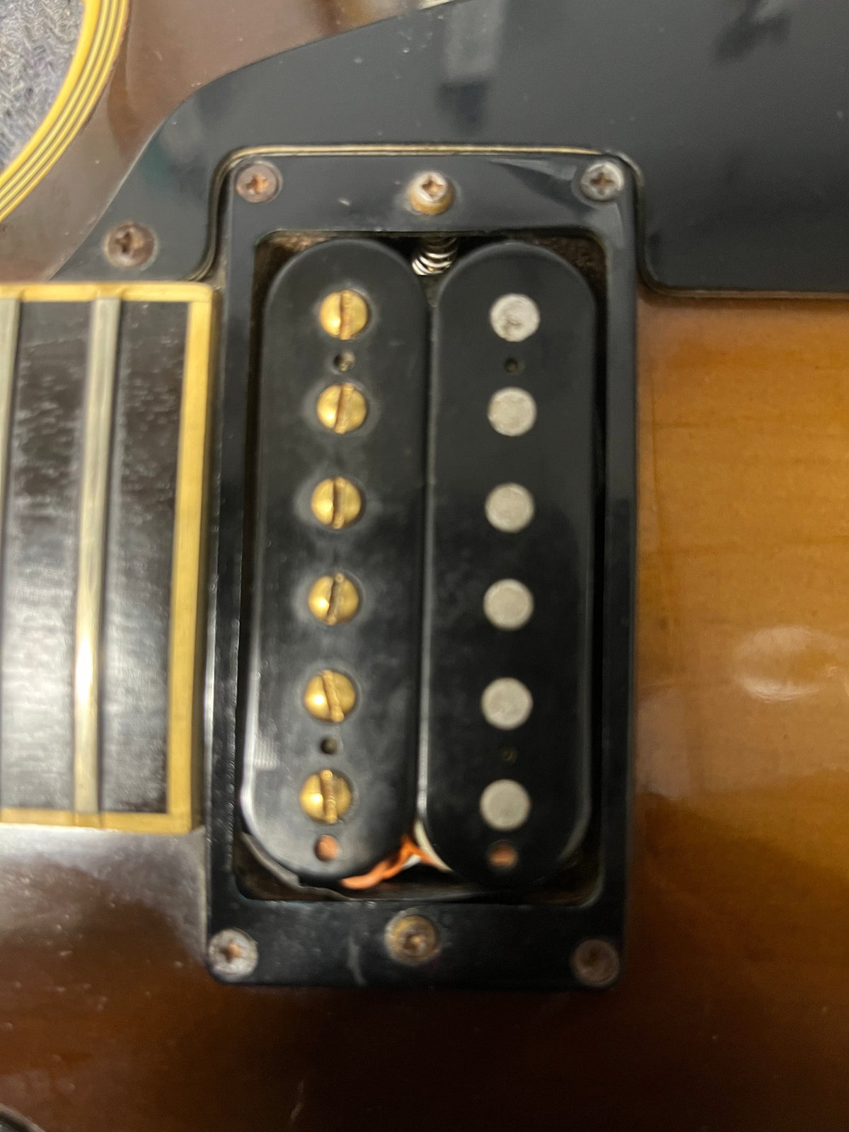 Close-up of a humbucker pickup with visible screws and pole pieces, mounted on a Gibson 1980 Les Paul Custom in Tobacco Sunburst finish.