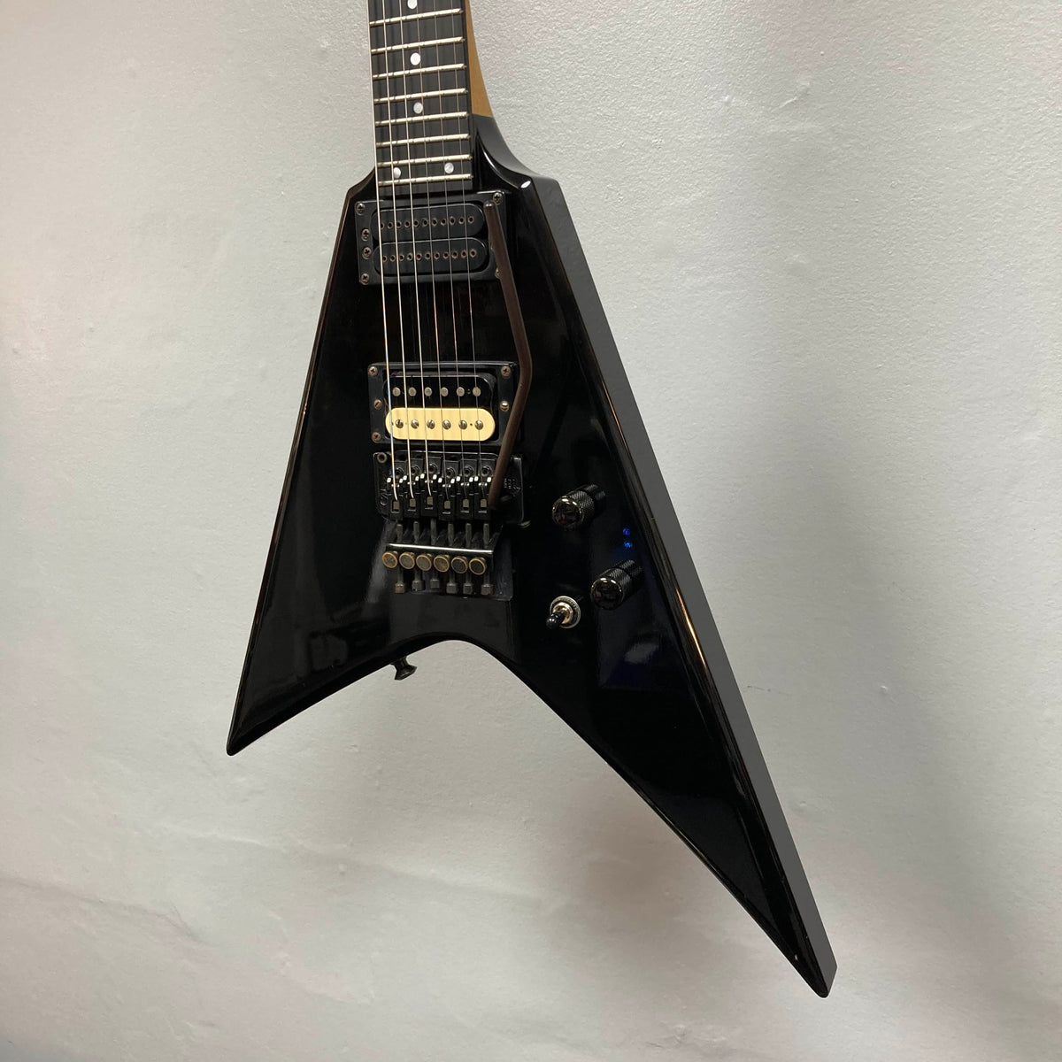 A black 1992 Carvin Ultra V USA electric guitar with a Kahler Steeler Trem, MJ-wound Seymour Duncan DCJ humbuckers, and multiple control knobs hangs against a light-colored wall.