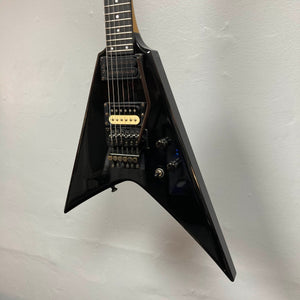 A black 1992 Carvin Ultra V USA electric guitar with a Kahler Steeler Trem, MJ-wound Seymour Duncan DCJ humbuckers, and multiple control knobs hangs against a light-colored wall.
