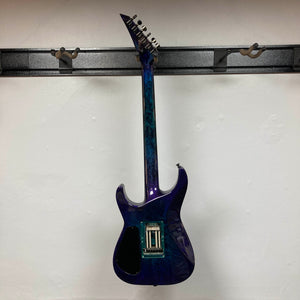 A 1995 Jackson SL1 Soloist Custom Shop electric guitar in Eerie Dess Swirl finish, currently without strings or pickups, is displayed on a black wall mount against a white background, highlighting its premium craftsmanship from Jackson’s USA Custom Shop.