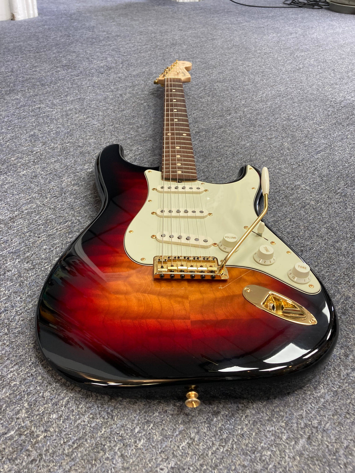 Fender Custom Shop 1960s Stratocaster 1998 on the floor, close-up of knobs and guitar neck, showcasing craftsmanship and vintage charm.