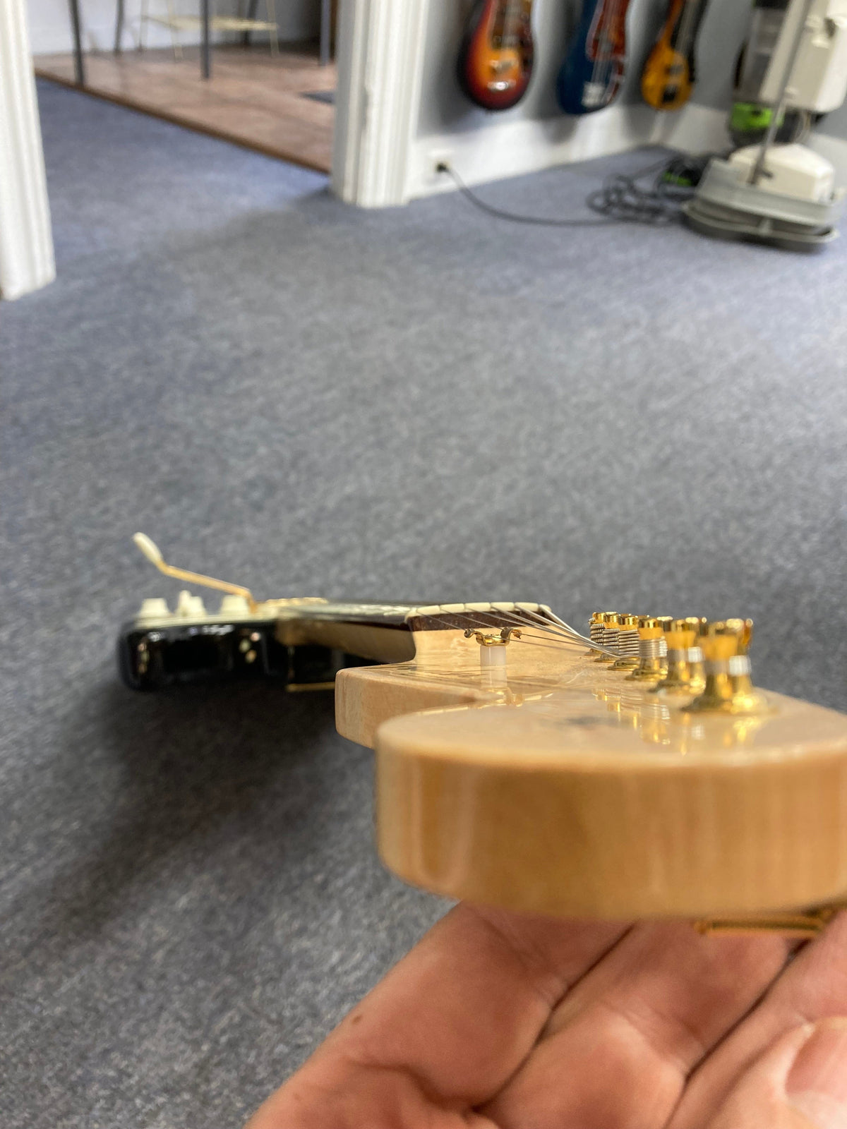 Hand holding a Fender Custom Shop 1960s FMT Stratocaster 1998 w/Case, showcasing its meticulous craftsmanship and iconic woodwork.