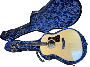 A 2005 Collings CJ BaA acoustic guitar with Brazilian rosewood back and sides and an Adirondack spruce top rests in an open, blue velvet-lined hard case.