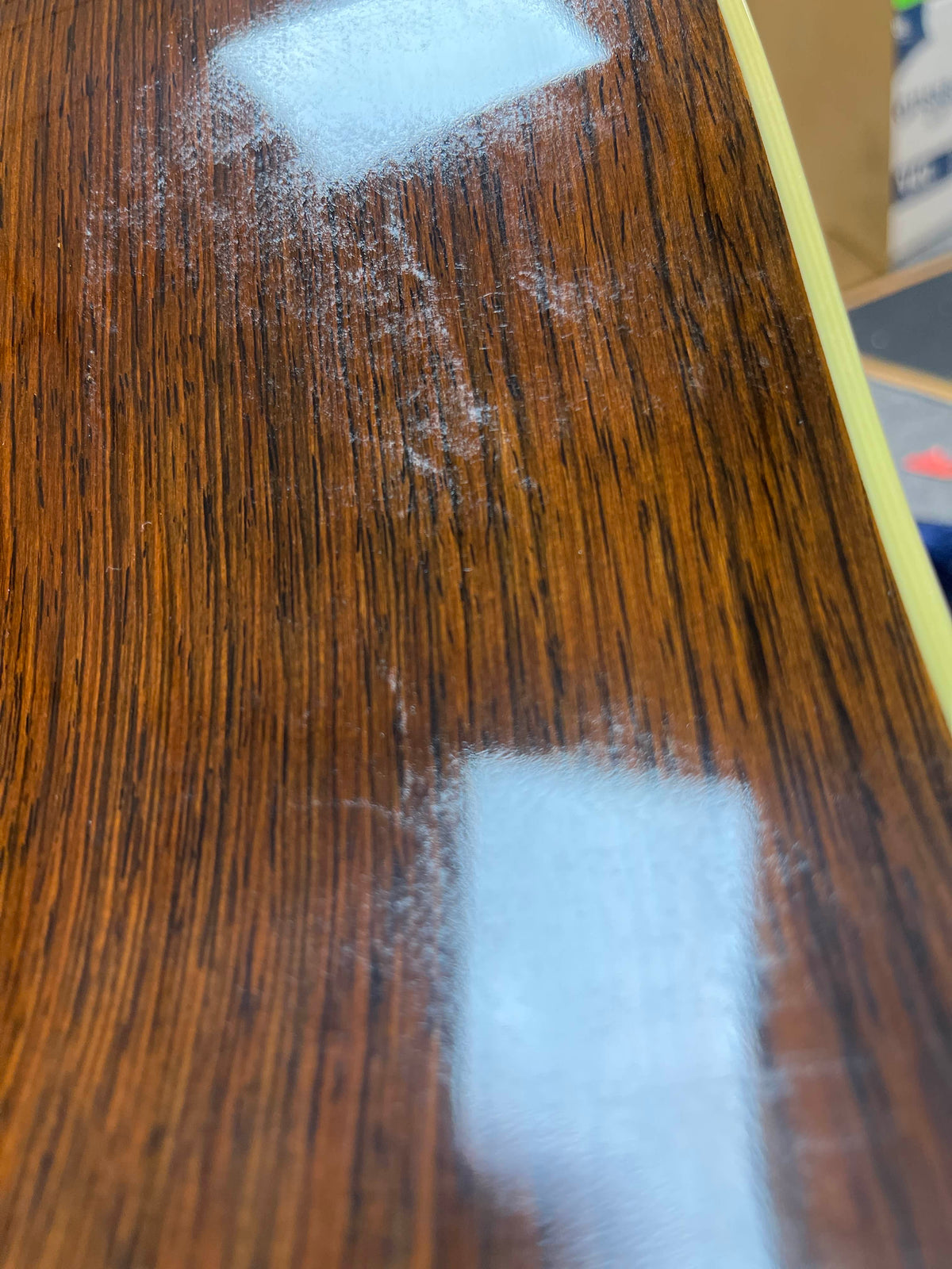 Close-up of a 2005 Collings CJ BaA (Brazilian Rosewood & Adirondack Spruce) guitar surface by Collings, showing white dust or residue on the finish under overhead lights.
