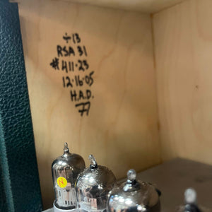 Vintage vacuum tubes with handwritten notes on a wooden surface