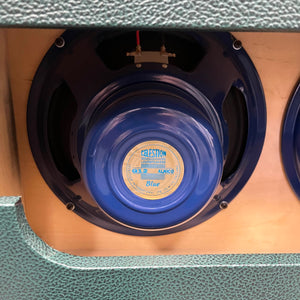 Close-up of a Celestion Alnico Blue speaker inside a textured green Divided by 13 RSA 31 2x12 cabinet, from the 2005 Divided by 13 RSA 31 Head with Matching Cabinet and Flight Case.