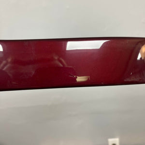 A close-up of a glossy 2007 Fender Standard Telecaster MIM Midnight Wine Red by Fender shows a small scratch near the center, surface reflections, and a light source. The background features a plain, light wall with an electrical outlet at the bottom.