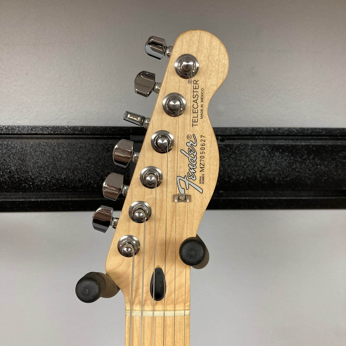 The image shows the headstock of a 2007 Fender Standard Telecaster MIM Midnight Wine Red, featuring six tuning pegs, the Fender logo, and serial number MN915987. The guitar rests in a holder against a gray wall.