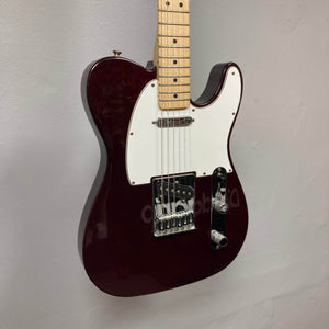 A close-up of a 2007 Fender Standard Telecaster MIM in Midnight Wine Red by Fender, featuring a white pickguard, maple neck, two control knobs, a switch, and single-coil pickups against a plain light-colored wall.