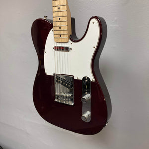 A close-up of a 2007 Fender Standard Telecaster MIM in Midnight Wine Red with single-coil pickups, white pickguard, chrome bridge, two-knob control panel, and maple neck, hanging on a plain light gray wall.
