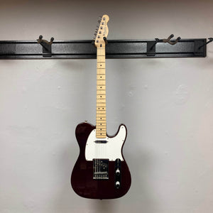 A 2007 Fender Standard Telecaster MIM in Midnight Wine Red with a white pickguard and single-coil pickups hangs on a black wall-mounted rack against a light gray wall.