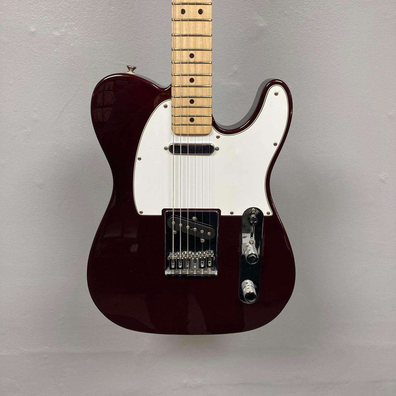 A 2007 Fender Standard Telecaster MIM in Midnight Wine Red with a white pickguard, two single-coil pickups, three knobs, and a maple neck, photographed against a plain light gray wall. A 2007 Fender Standard Telecaster MIM in Midnight Wine Red with a white pickguard, two single-coil pickups, three knobs, and a maple neck, photographed against a plain light gray wall.