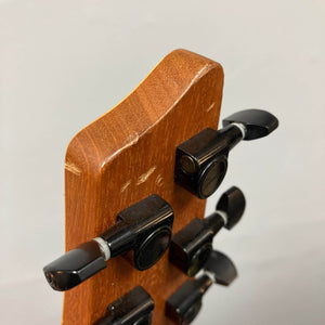 Close-up of the back of a 2009 Godin Summit CT w/Carved Flame Maple Cap headstock, featuring four black tuning pegs and visible scratches on the wood surface.