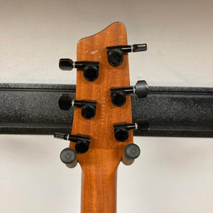 The back of a 2009 Godin Summit CT w/Carved Flame Maple Cap headstock features six black tuning pegs, highlighting the wooden neck of this electric guitar with a metal rail visible in the background.