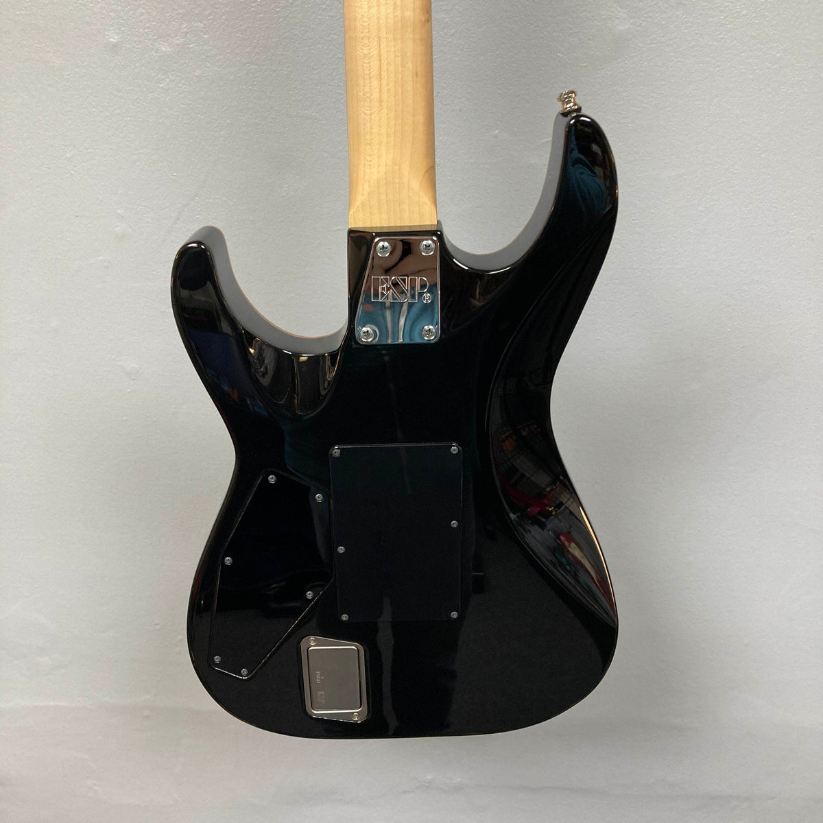The back of a 2019 ESP USA M-II Purple Haze Burst electric guitar, featuring a natural wood neck and an “ESP” label on the metal neck plate, is displayed against a plain light background. Crafted in the USA by ESP, this guitar highlights superior craftsmanship and striking style.