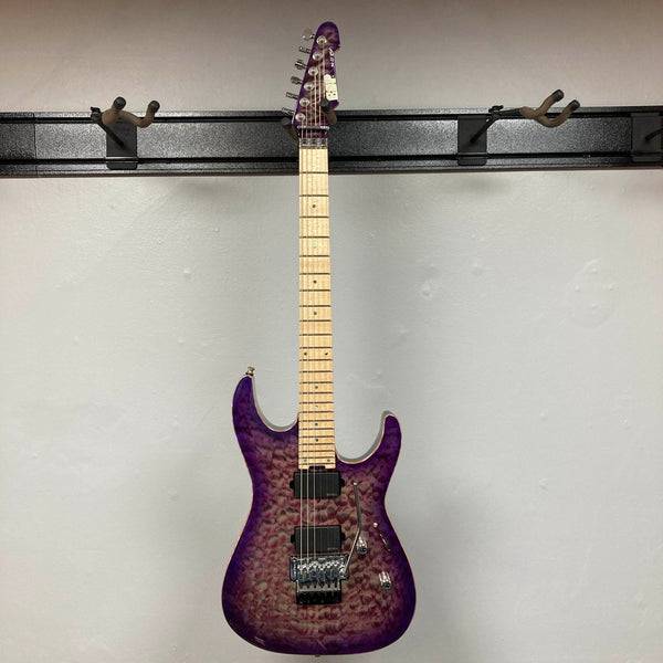 The 2019 ESP USA M-II Purple Haze Burst w/Case, crafted in the USA by ESP, features a stunning quilted maple top in Purple Haze Burst, two black humbucker pickups, a maple fretboard, and a Floyd Rose tremolo bridge—photographed here against a plain light gray wall.
