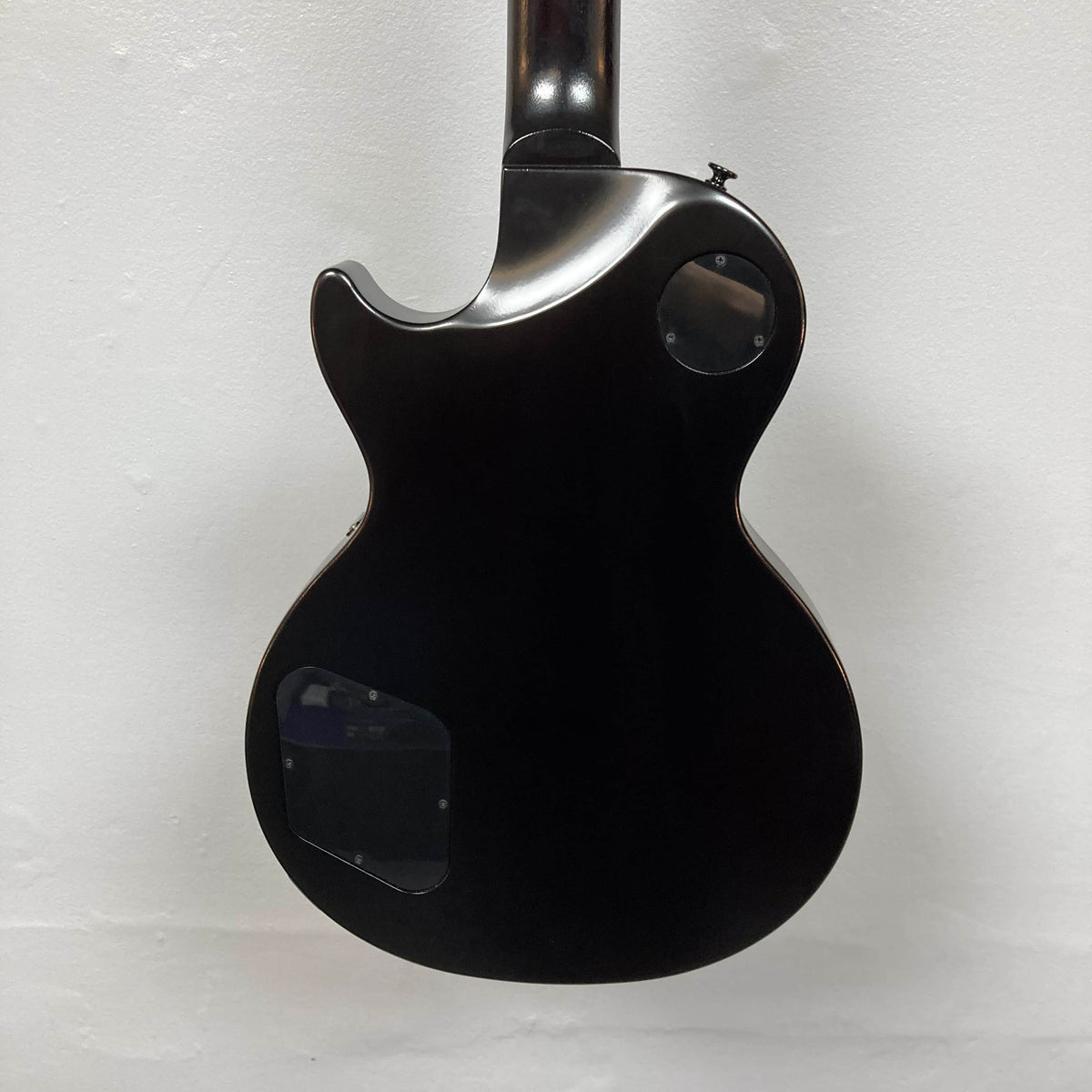 The back of the 2025 Gibson Les Paul Studio Modern in Smokehouse Satin features two plastic cover plates and is displayed against a plain white background.
