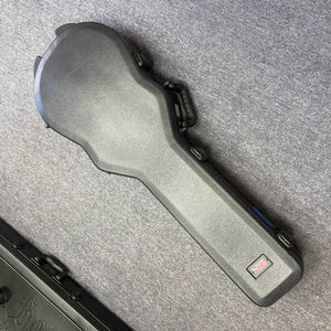 A Gator molded case for the 2025 Gibson Les Paul Studio Modern in Smokehouse Satin by Gibson lies closed on a gray carpeted floor.
