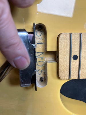 A close-up of a hand lifting the pickup on a Fender Custom Shop '51 Reissue Nocaster NOS 2006, revealing "5-31 50 N O S" markings in the cavity next to a maple neck with black dot inlay on this vintage-style Fender guitar.