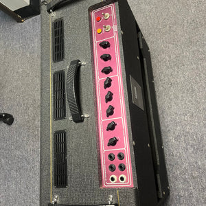 A 2004 Vox AC30/6TB amplifier head by Vox, made in England with Celestion Alnico Blues speakers, featuring a black body and pink control panel with knobs and switches, sits on a gray carpeted floor.