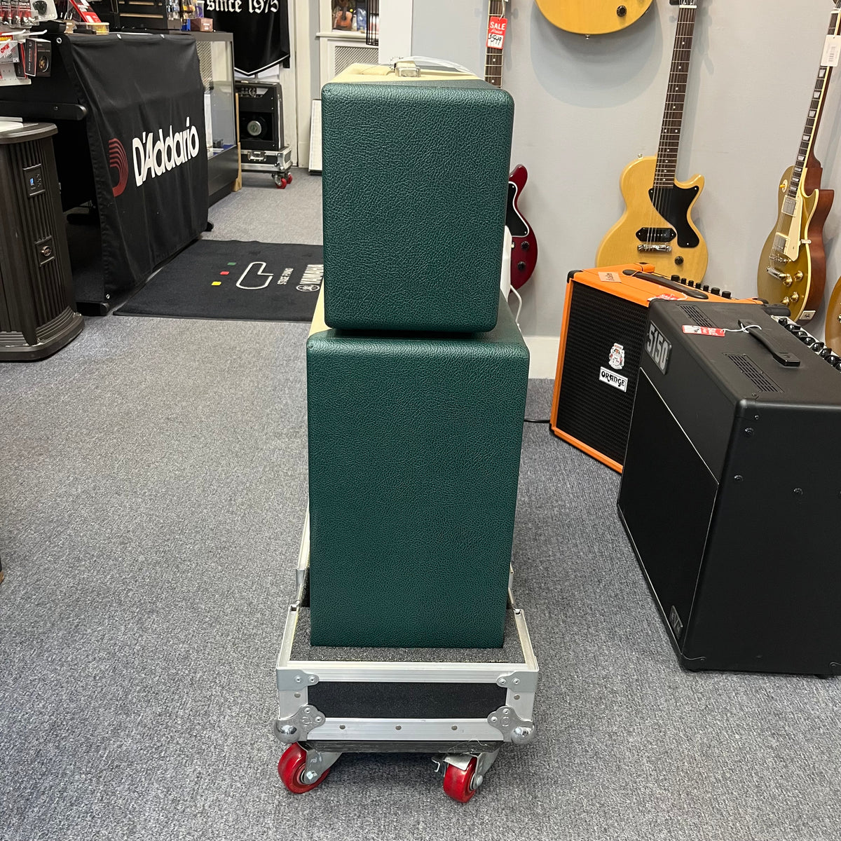 A 2005 Divided by 13 RSA 31 head with matching 2x12 cabinet and flight case is stacked on a metal rolling cart inside a music store, with guitars and amplifiers visible in the background. Local pickup only.